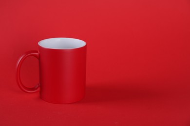 Photo of One blank mug on red background. Mockup for design