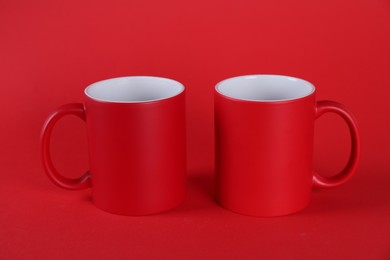 Two blank mugs on red background. Mockup for design