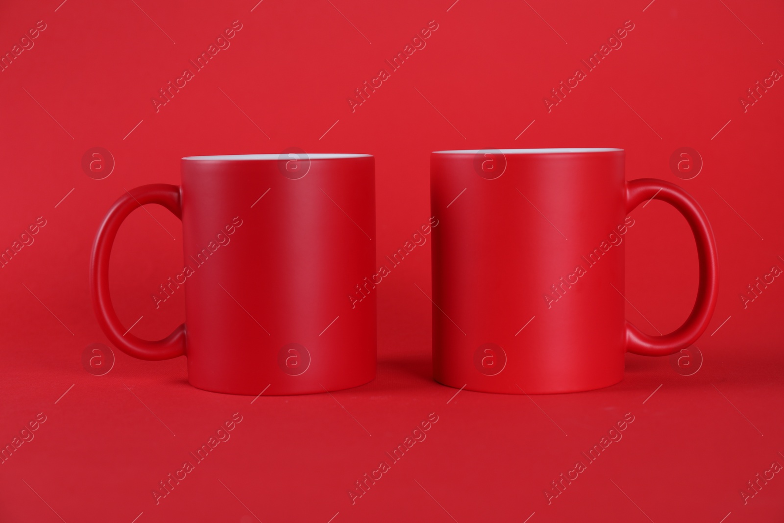 Photo of Two blank mugs on red background. Mockup for design