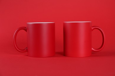 Photo of Two blank mugs on red background. Mockup for design