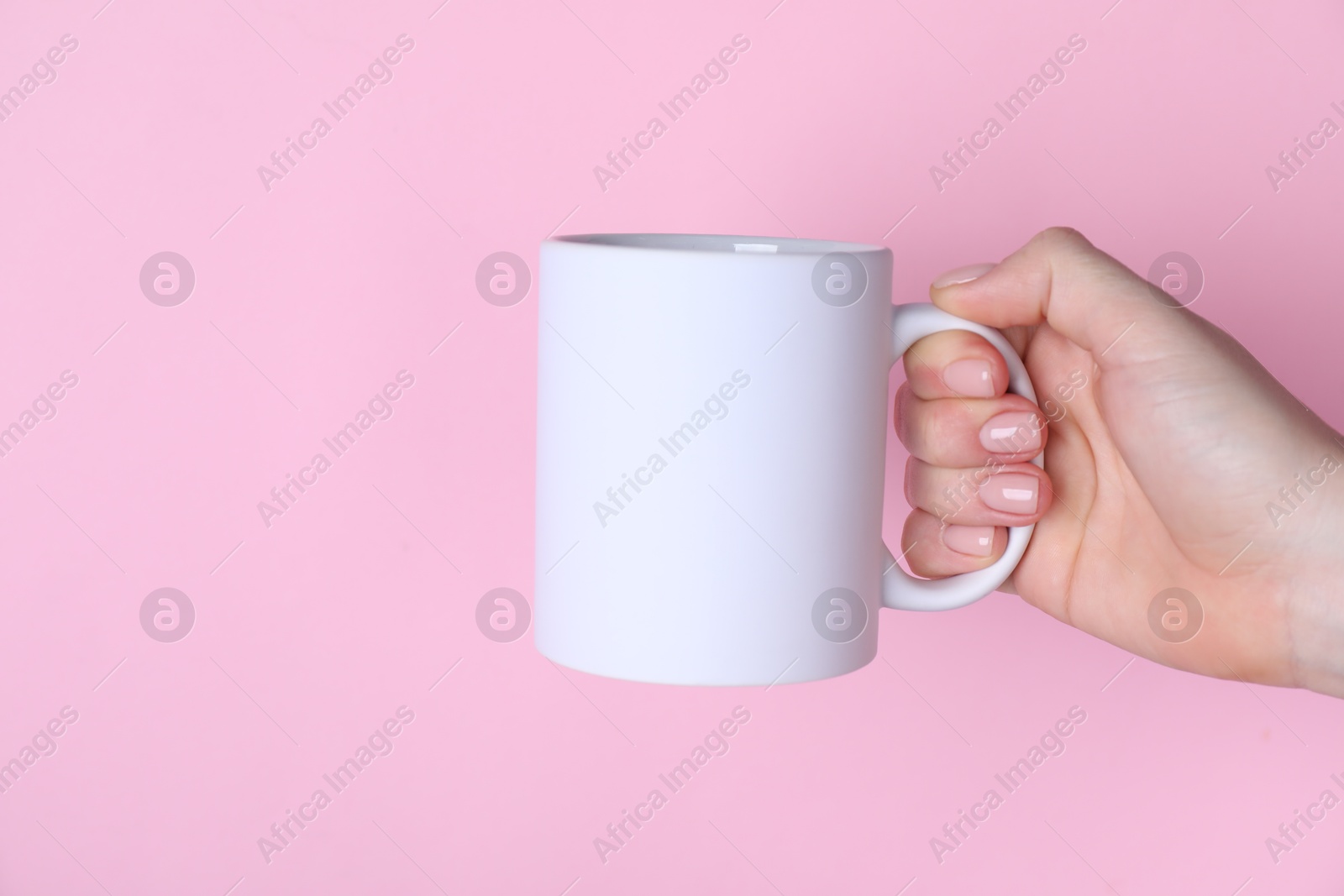 Photo of Woman holding blank white mug on pink background, closeup. Mockup for design