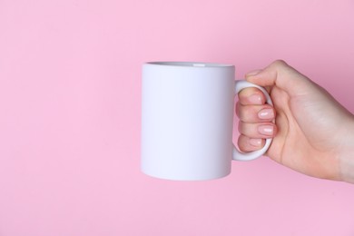 Photo of Woman holding blank white mug on pink background, closeup. Mockup for design