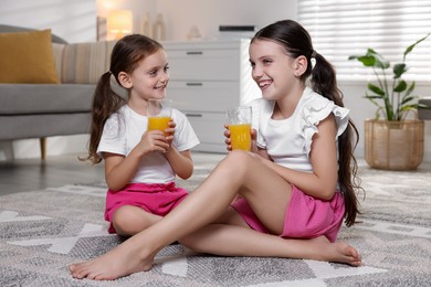 Photo of Cute little sisters with glasses of juice at home