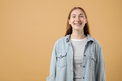 Photo of Smiling girl with braces on beige background, space for text