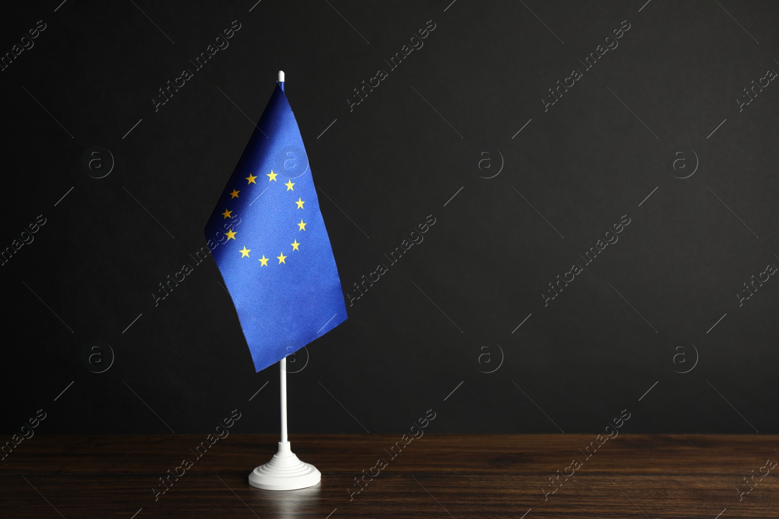 Photo of One flag of European Union on wooden table against black background. Space for text