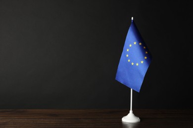 Photo of One flag of European Union on wooden table against black background. Space for text