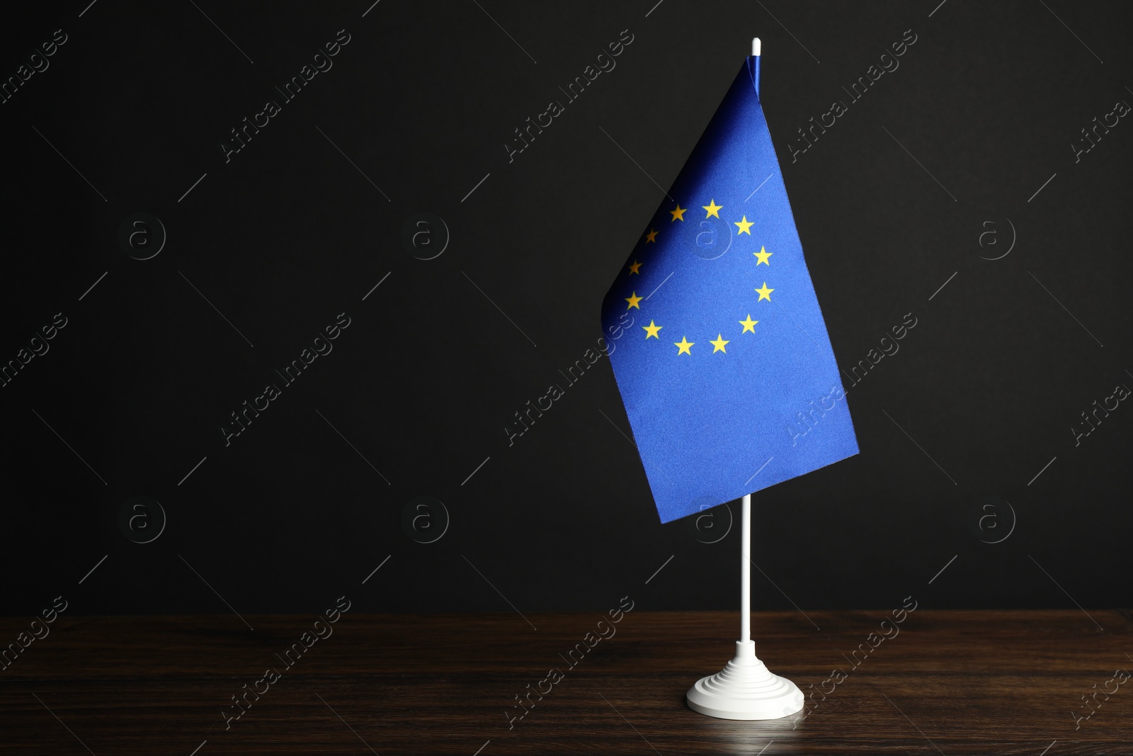 Photo of One flag of European Union on wooden table against black background. Space for text