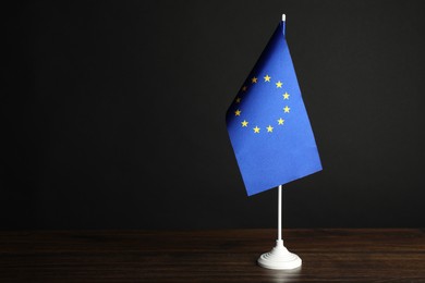 Photo of One flag of European Union on wooden table against black background. Space for text