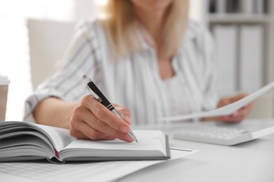 Photo of Budget planning. Woman with document taking notes at table indoors, closeup