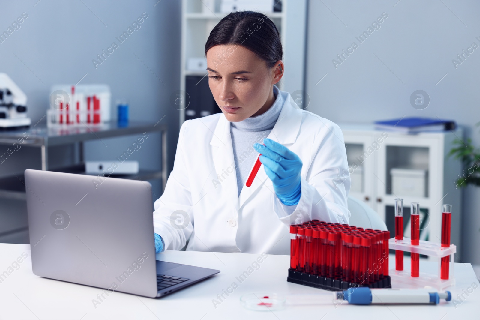 Photo of Laboratory testing. Doctor holding test tube with blood sample at table indoors