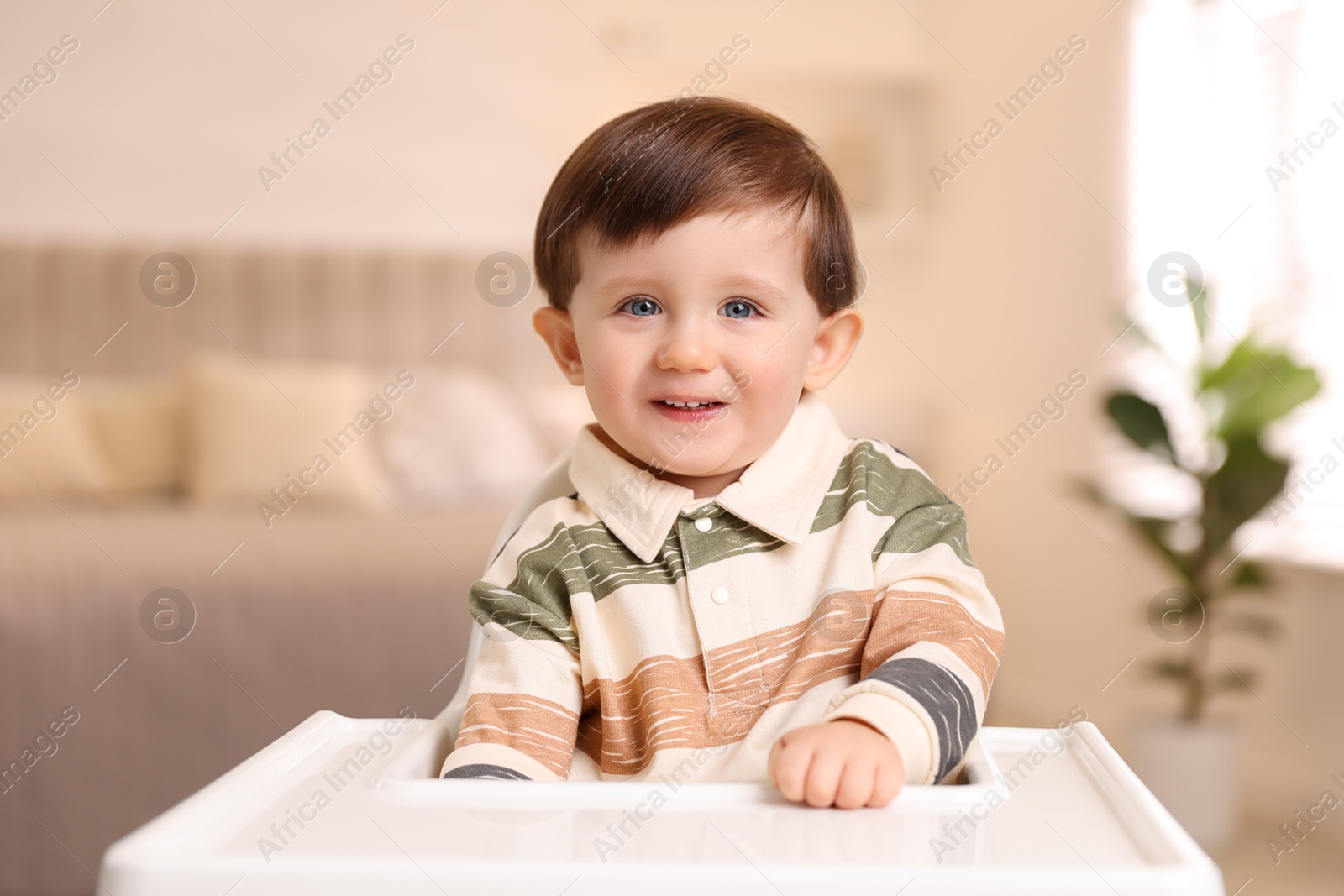 Photo of Cute little kid sitting in high chair at home