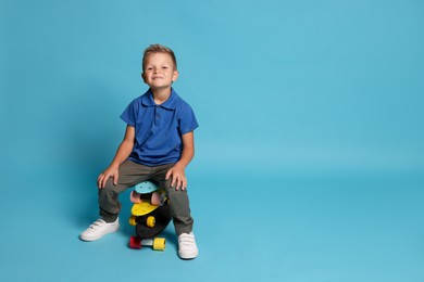 Photo of Little boy with skateboards on light blue background, space for text