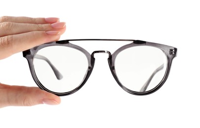 Photo of Woman holding glasses with grey frame on white background, closeup