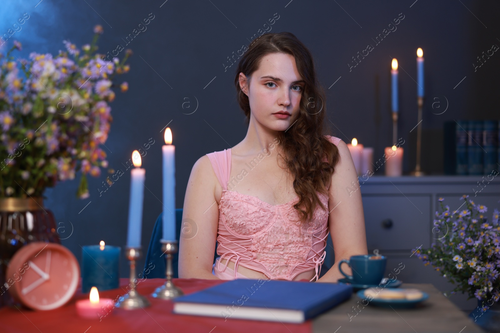 Photo of Beautiful young woman sitting at table in room. Fashion vintage style portrait