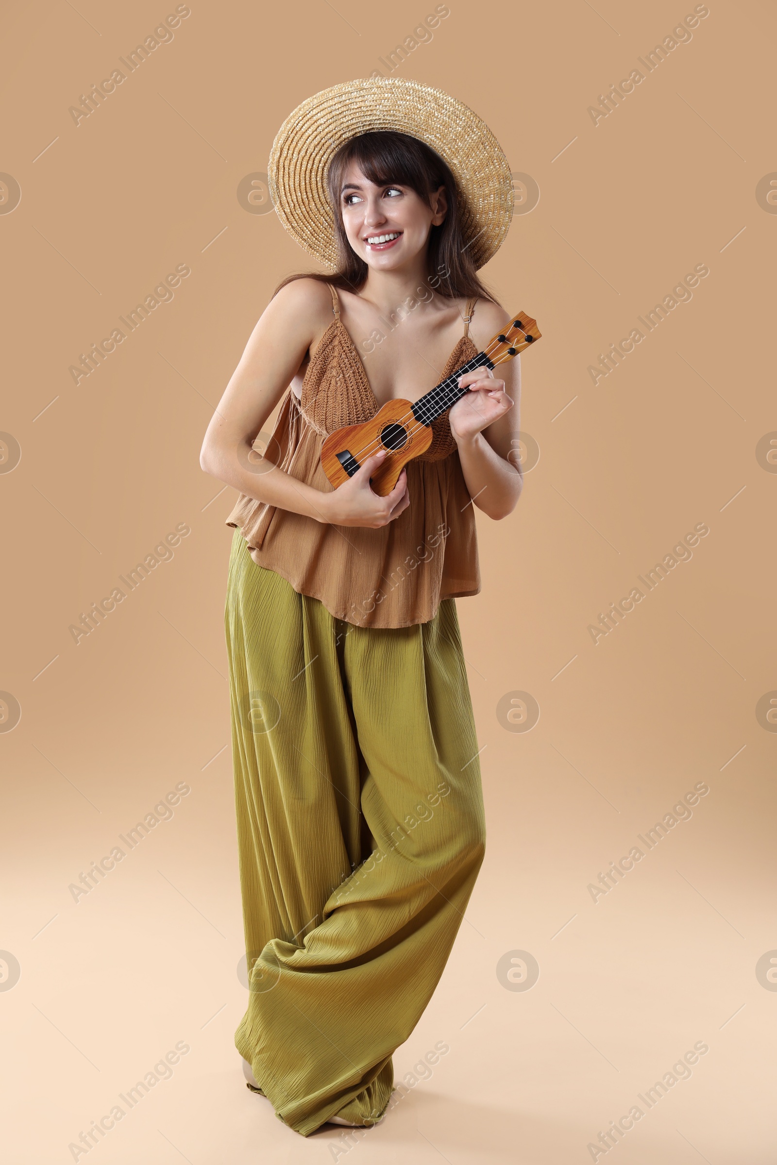 Photo of Happy woman playing ukulele on beige background