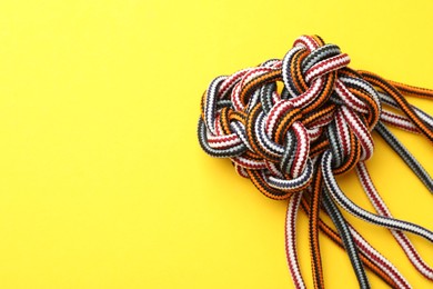 Photo of Braided colorful ropes on yellow background, top view with space for text. Unity concept