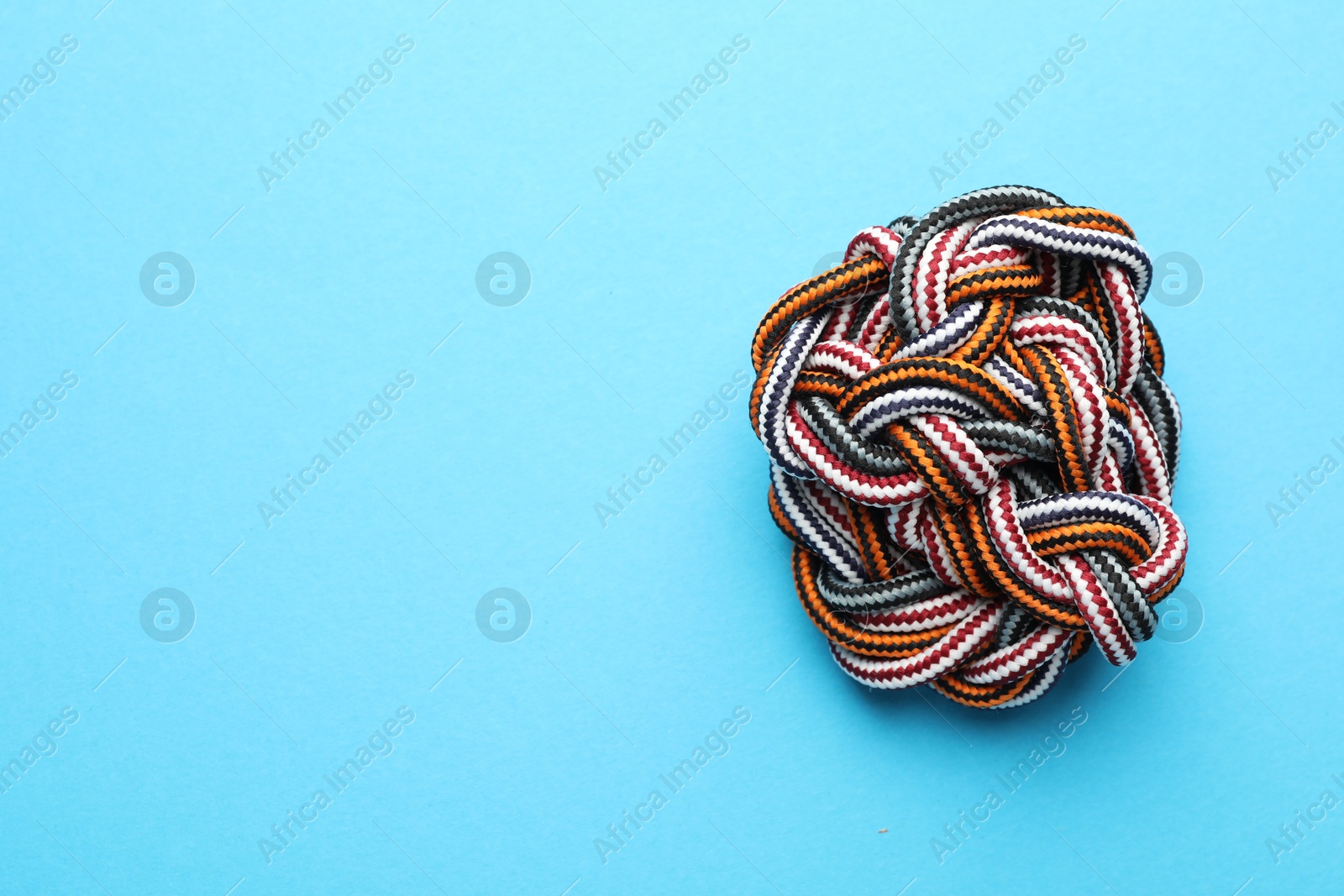 Photo of Colorful ropes tied together on light blue background, top view with space for text. Unity concept