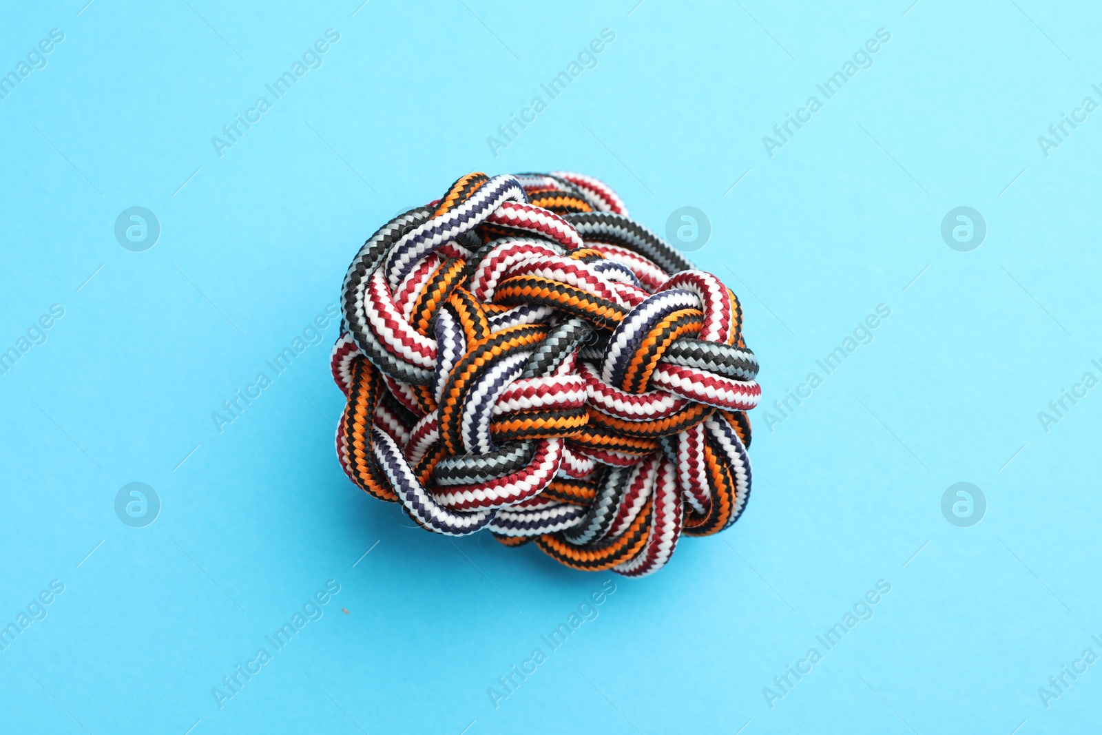 Photo of Colorful ropes tied together on light blue background, top view. Unity concept