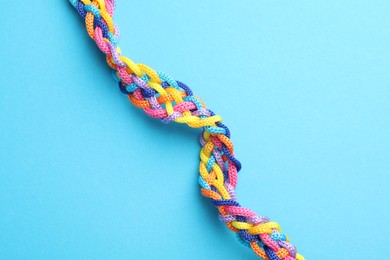 Photo of Braided colorful ropes on light blue background, top view. Unity concept