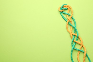 Photo of Braided colorful ropes on green background, top view with space for text. Unity concept