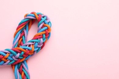 Photo of Braided colorful ropes on pink background, top view with space for text. Unity concept