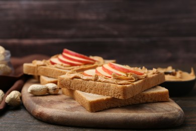 Photo of Tasty sandwiches with peanut butter and apple on wooden table, closeup