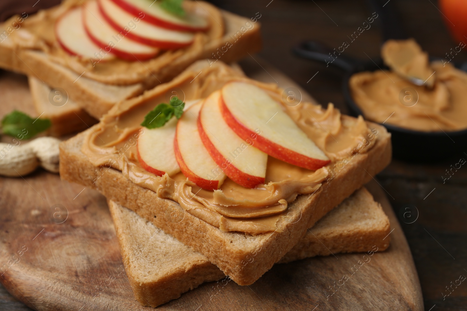 Photo of Tasty sandwiches with peanut butter, apple and mint on table, closeup