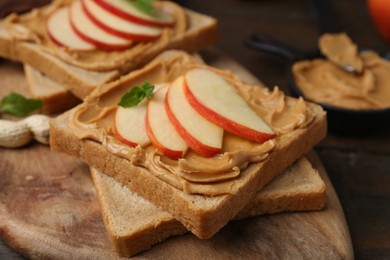 Photo of Tasty sandwiches with peanut butter, apple and mint on table, closeup