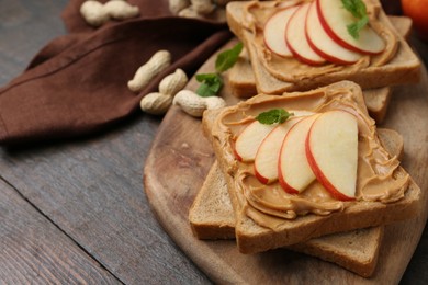 Photo of Tasty sandwiches with peanut butter, apple, nuts and mint on wooden table, closeup