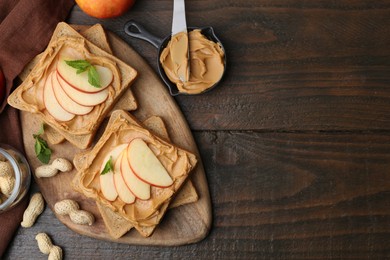 Photo of Tasty sandwiches with peanut butter, apple, nuts and mint on wooden table, flat lay. Space for text