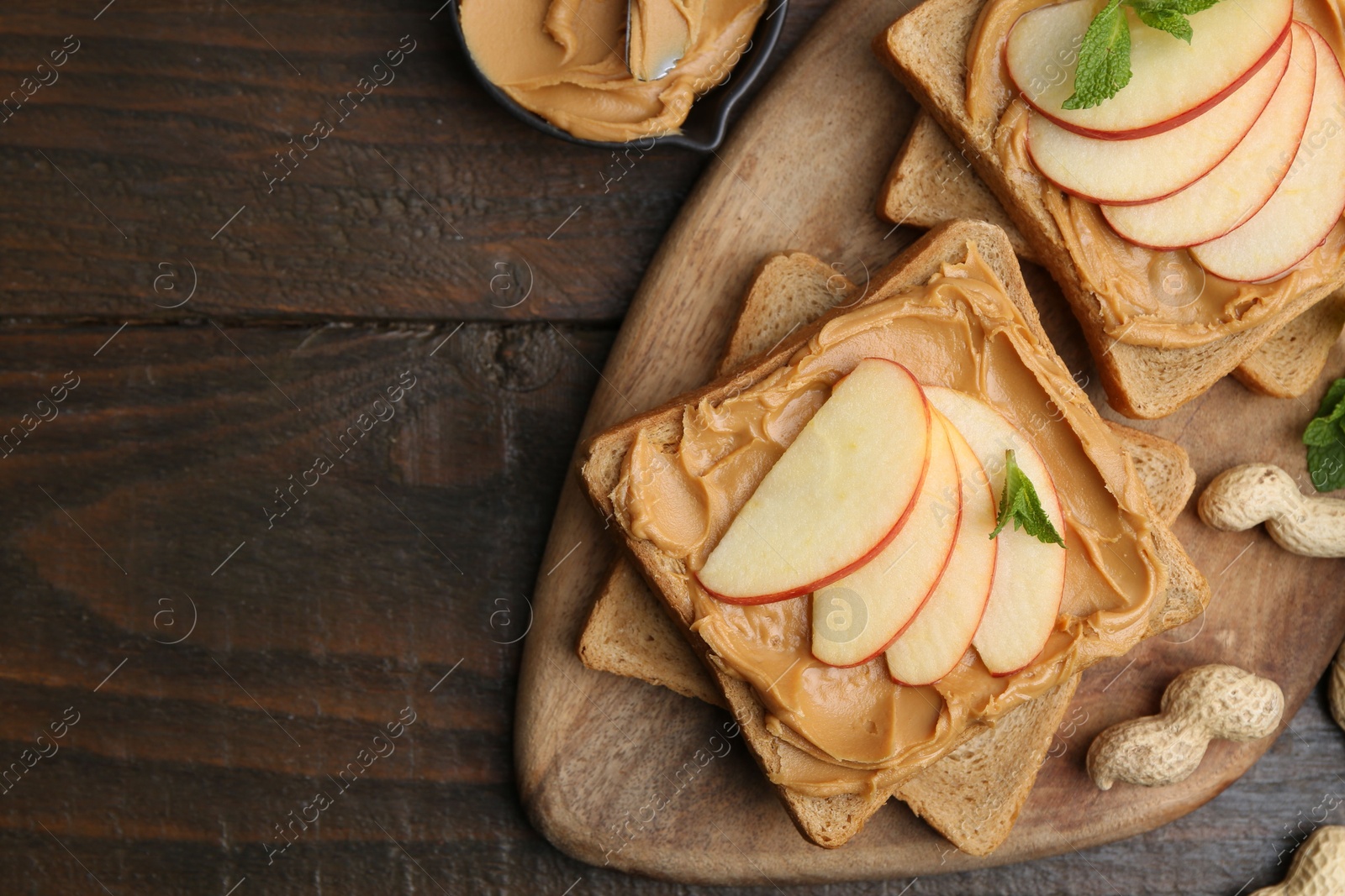 Photo of Tasty sandwiches with peanut butter, apple, nuts and mint on wooden table, flat lay. Space for text