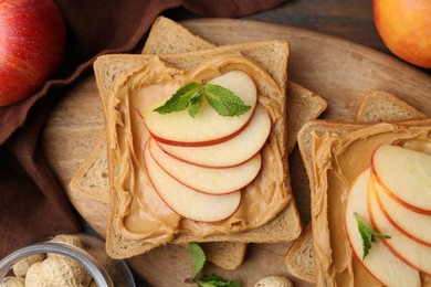 Photo of Tasty sandwiches with peanut butter, apples and mint on table, flat lay