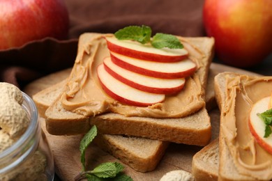 Photo of Tasty sandwiches with peanut butter, apples and mint on table, closeup