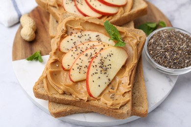 Photo of Tasty sandwiches with peanut butter, apple, chia seeds and mint on white table, closeup