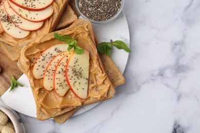 Photo of Tasty sandwiches with peanut butter, apple, chia seeds and mint on white marble table, flat lay. Space for text