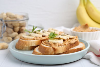 Photo of Tasty sandwiches with peanut butter, banana, chia seeds and mint on white table, closeup