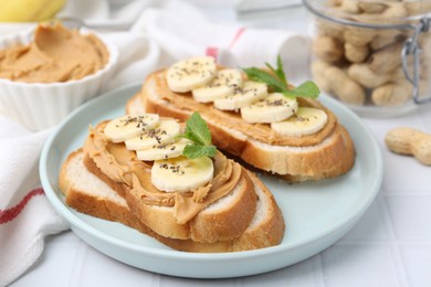 Photo of Tasty sandwiches with peanut butter, banana, chia seeds and mint on white table, closeup