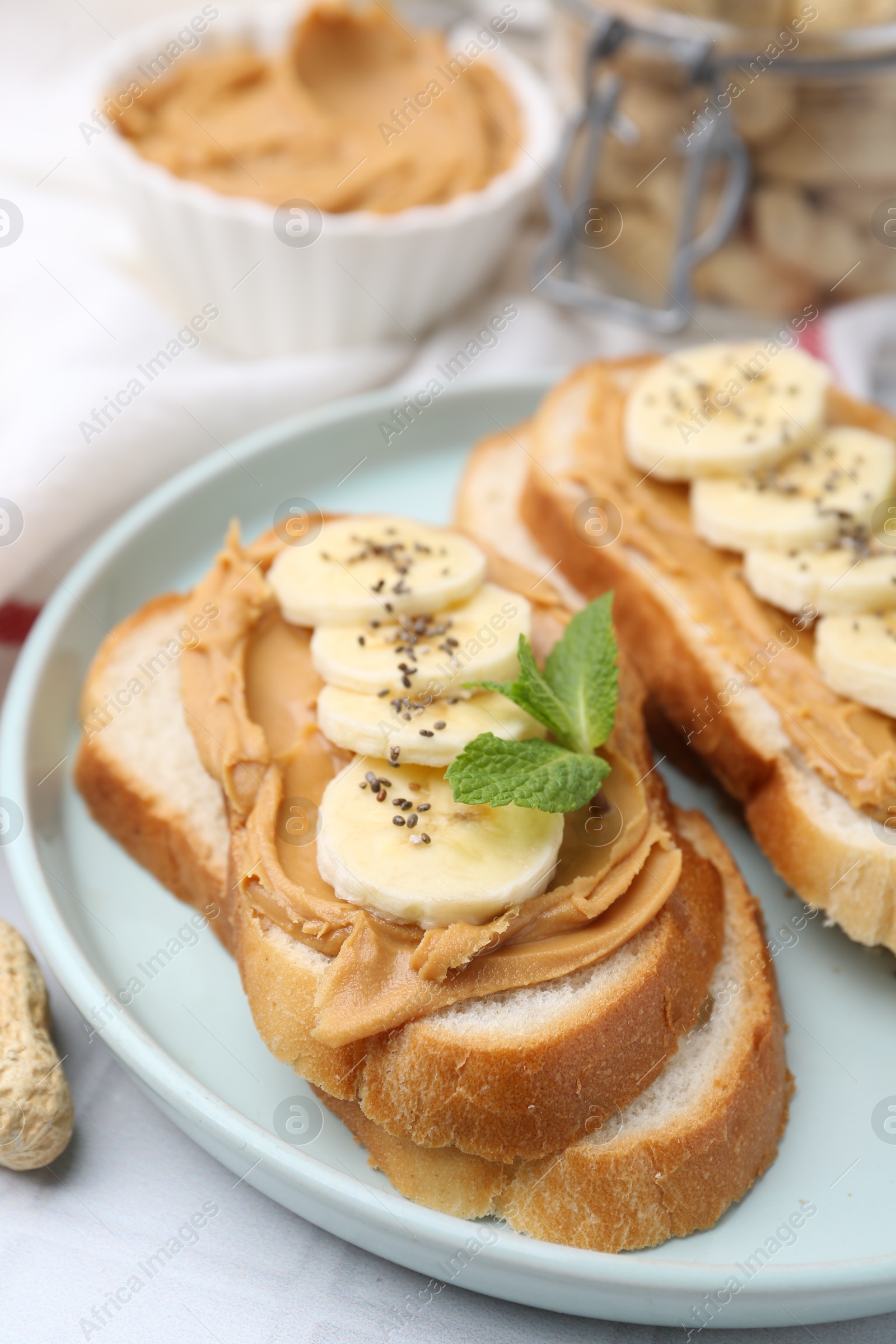 Photo of Tasty sandwiches with peanut butter, banana, chia seeds and mint on table, closeup