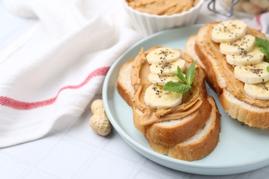 Photo of Tasty sandwiches with peanut butter, banana, chia seeds and mint on white table, closeup