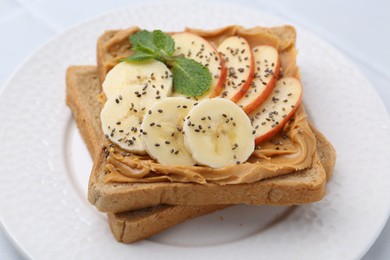 Photo of Tasty sandwich with peanut butter, apple, banana, chia seeds and mint on table, closeup