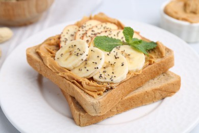 Photo of Tasty sandwich with peanut butter, apple, banana, chia seeds and mint on table, closeup