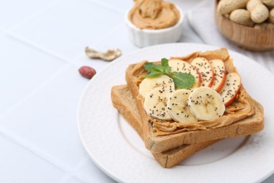 Photo of Tasty sandwich with peanut butter, apple, banana, chia seeds and mint on white table, closeup