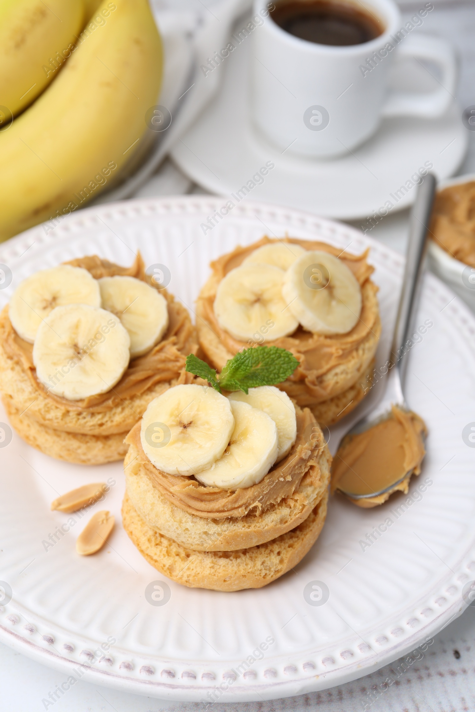 Photo of Tasty sandwiches with peanut butter, banana, mint and spoon on table, closeup