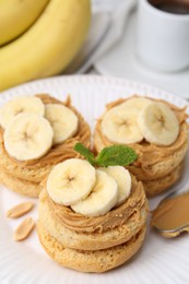 Photo of Tasty sandwiches with peanut butter, banana, mint and spoon on table, closeup