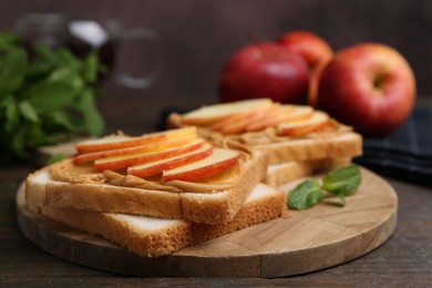 Photo of Tasty sandwiches with peanut butter, apples and mint on wooden table, closeup