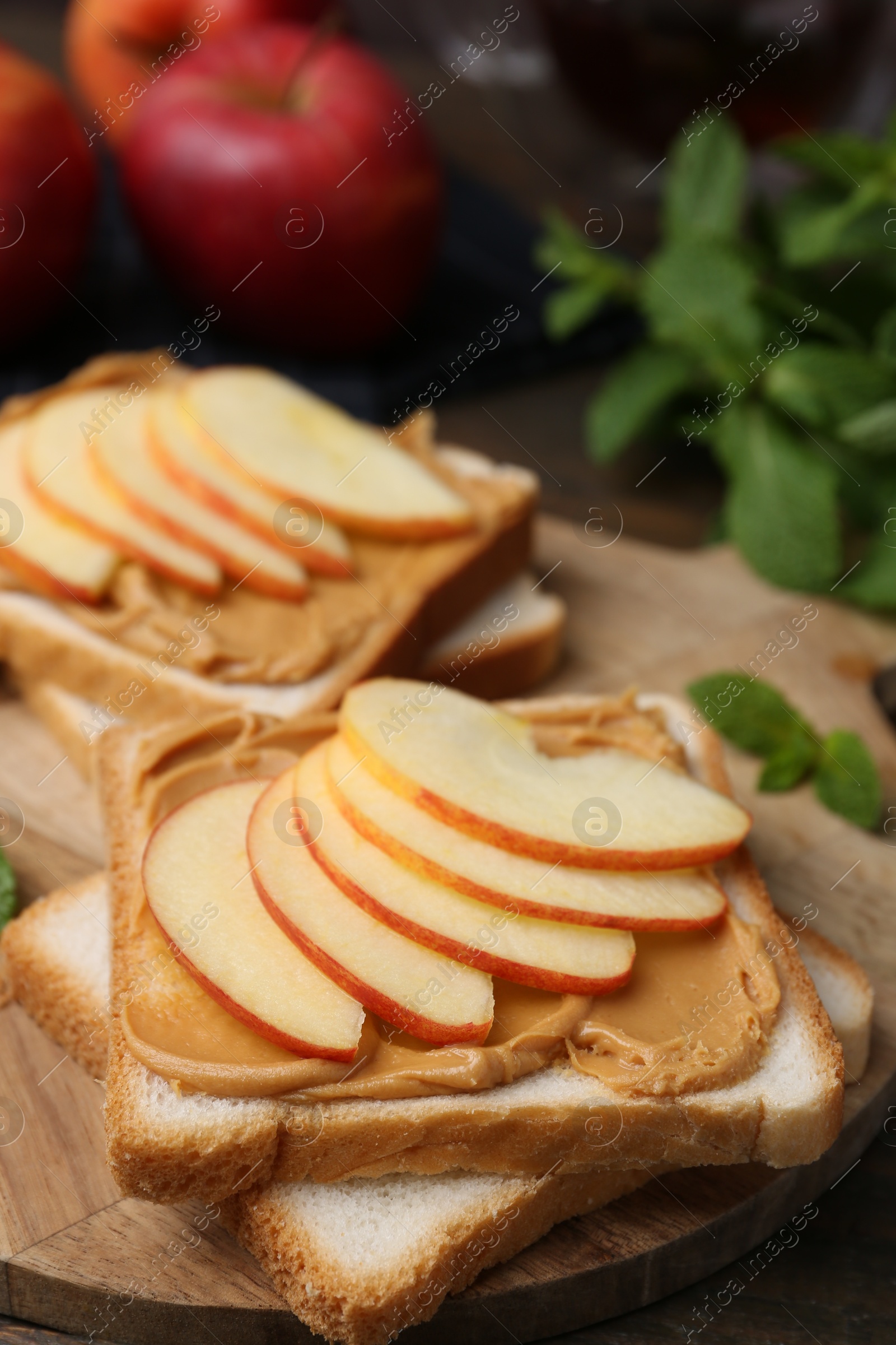 Photo of Tasty sandwiches with peanut butter, apples and mint on table, closeup