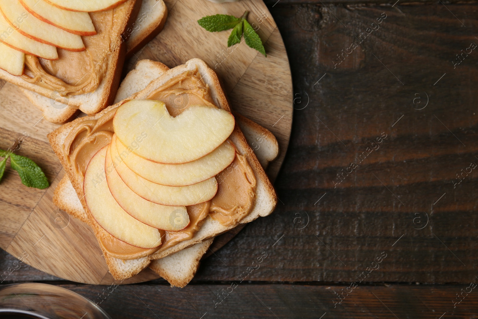 Photo of Tasty sandwiches with peanut butter, apple and mint on wooden table, top view. Space for text