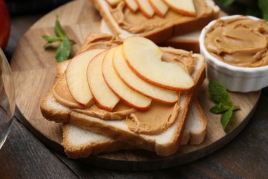 Photo of Tasty sandwiches with peanut butter, apple and mint on wooden table, closeup