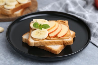 Photo of Tasty sandwich with peanut butter, apple, banana and mint on grey table, closeup