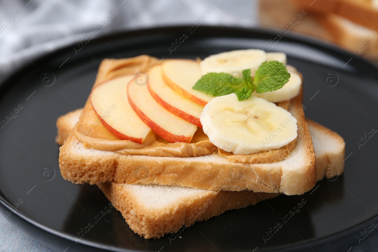 Photo of Tasty sandwich with peanut butter, apple, banana and mint on table, closeup